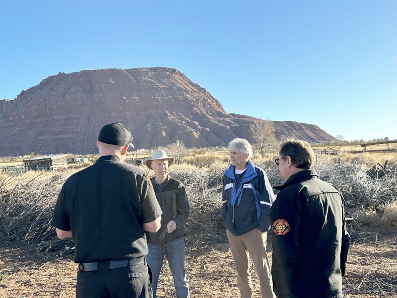 Ivins fire officials join Warren and botanist Terrence Walters, second from right, at the corral where Tamarisk debris is currently stored.