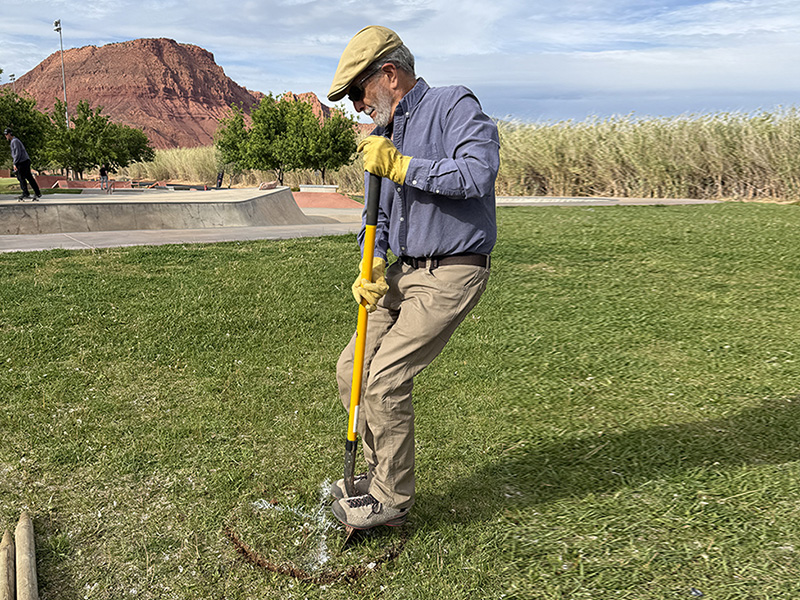 DPI member and Ivins City Councilman Wayne Pennington digs at a designated planting spot next to the skate park area at Unity Park