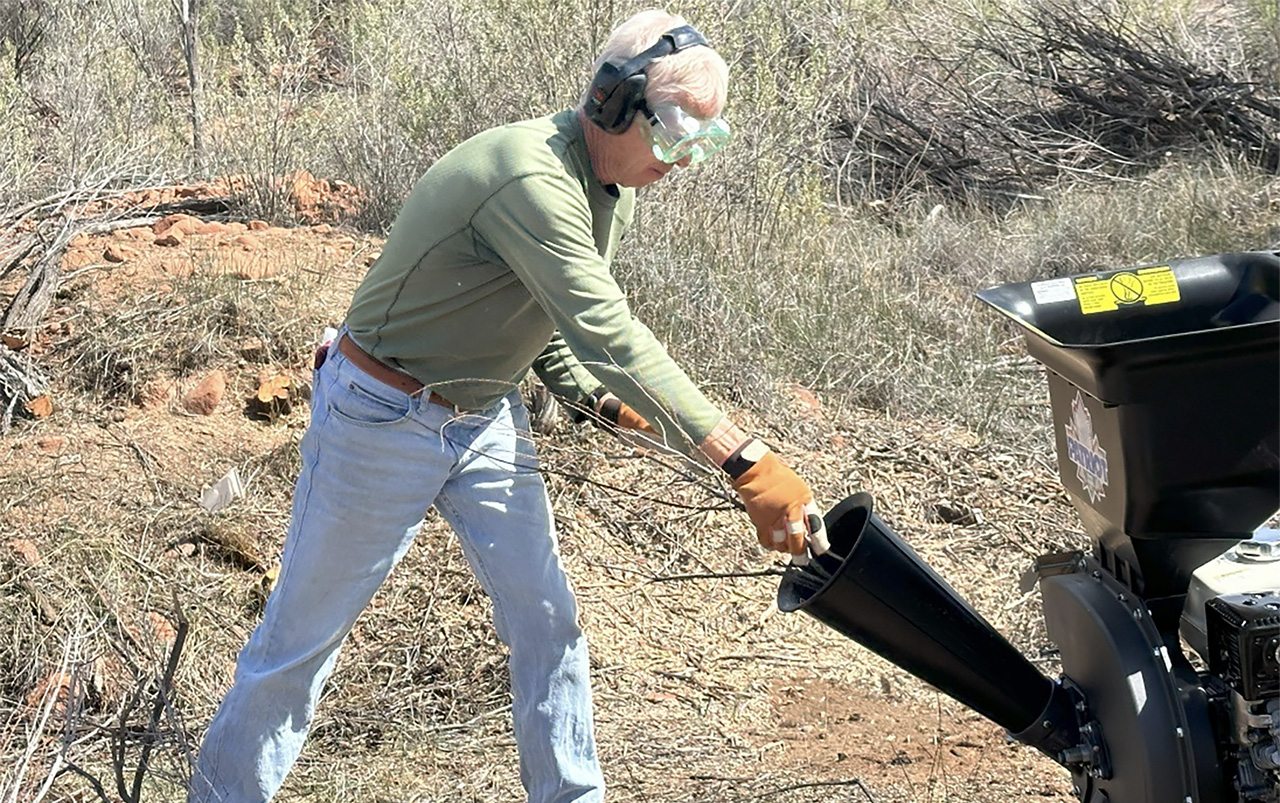 Chuck Warren demonstrates feeding the chipper, using proper protection for both eyes and ears.